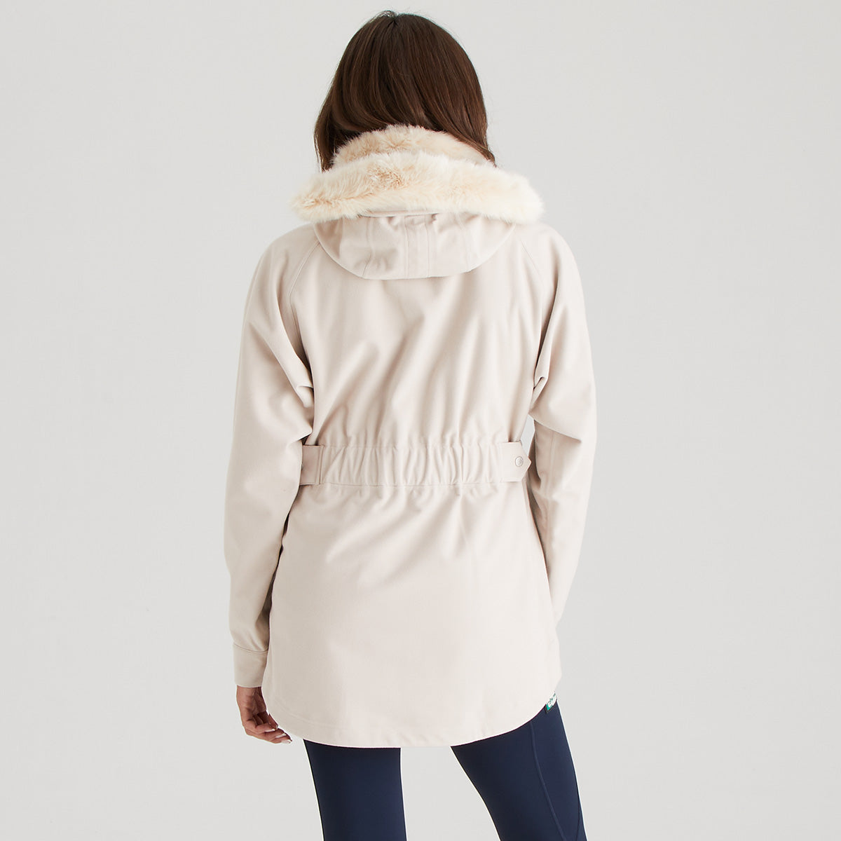 Person wearing a cream parka with fur trim on a plain background