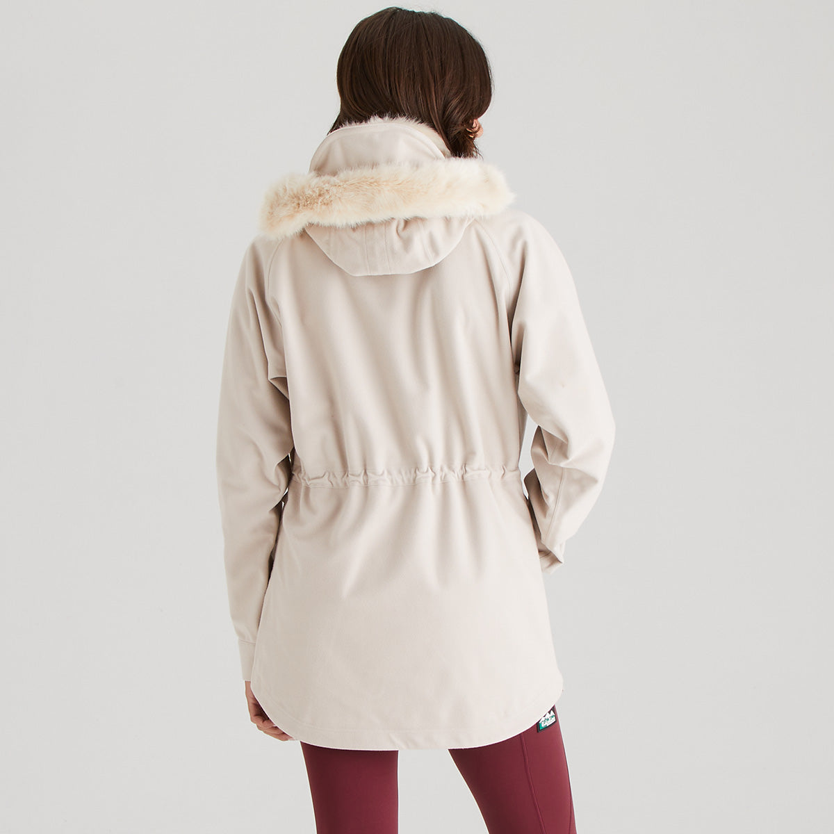 Person wearing a cream parka with fur hood on a light gray background