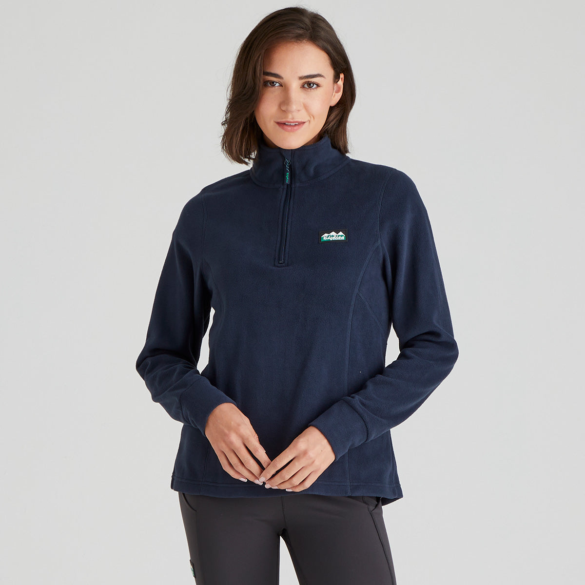 Woman wearing a navy blue pullover with a logo on a light grey background