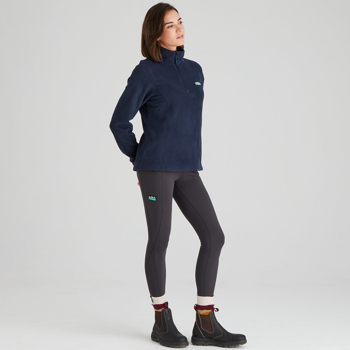 Woman wearing a navy fleece pullover and black leggings on a light grey background