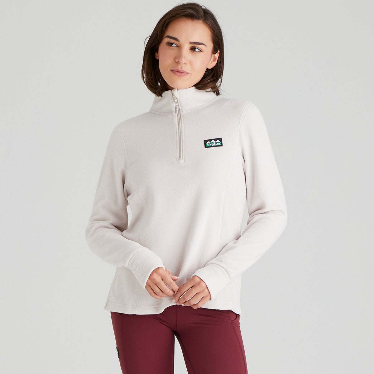 Woman wearing a white pullover with a logo on a light grey background