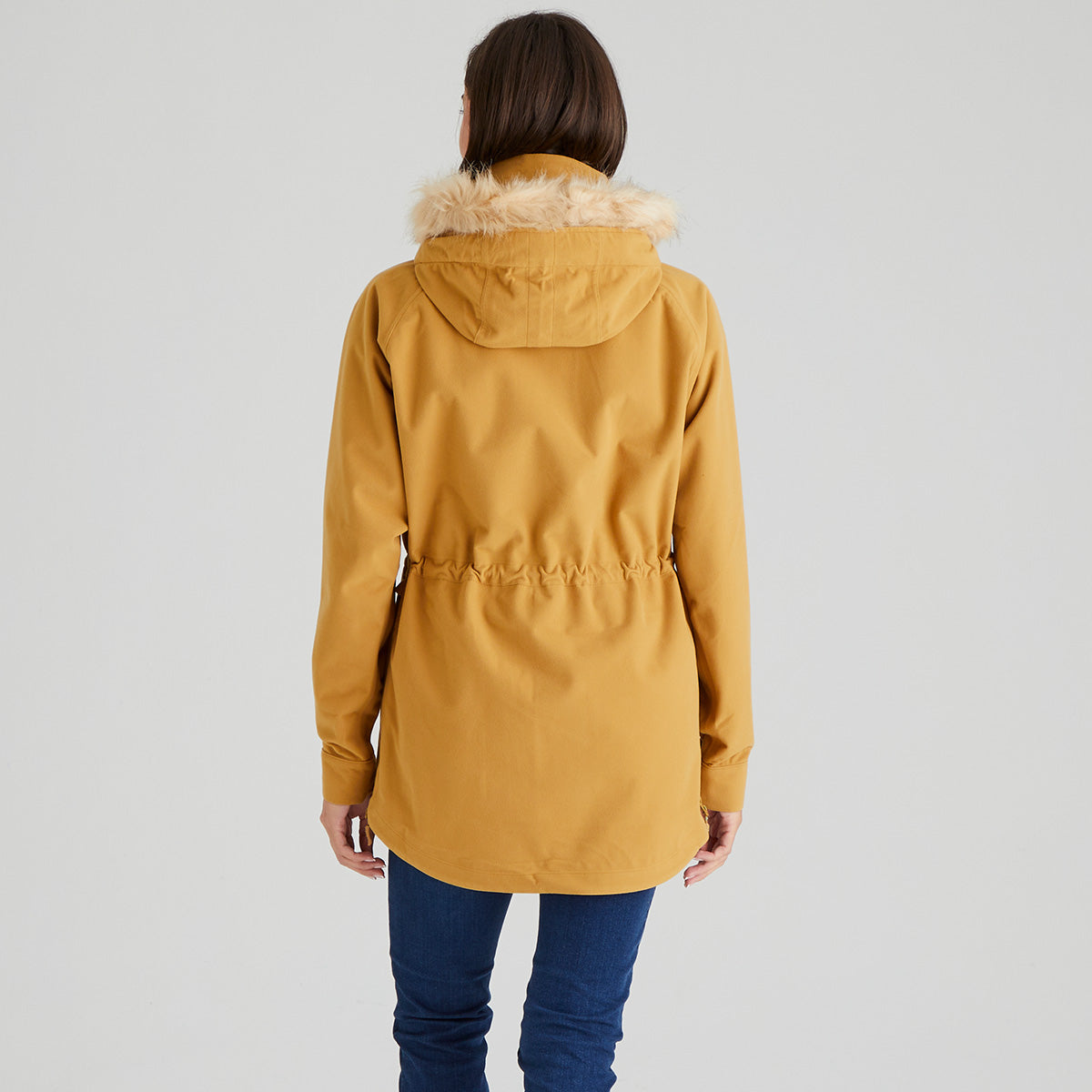 Person wearing a mustard yellow parka with fur hood on a light gray background