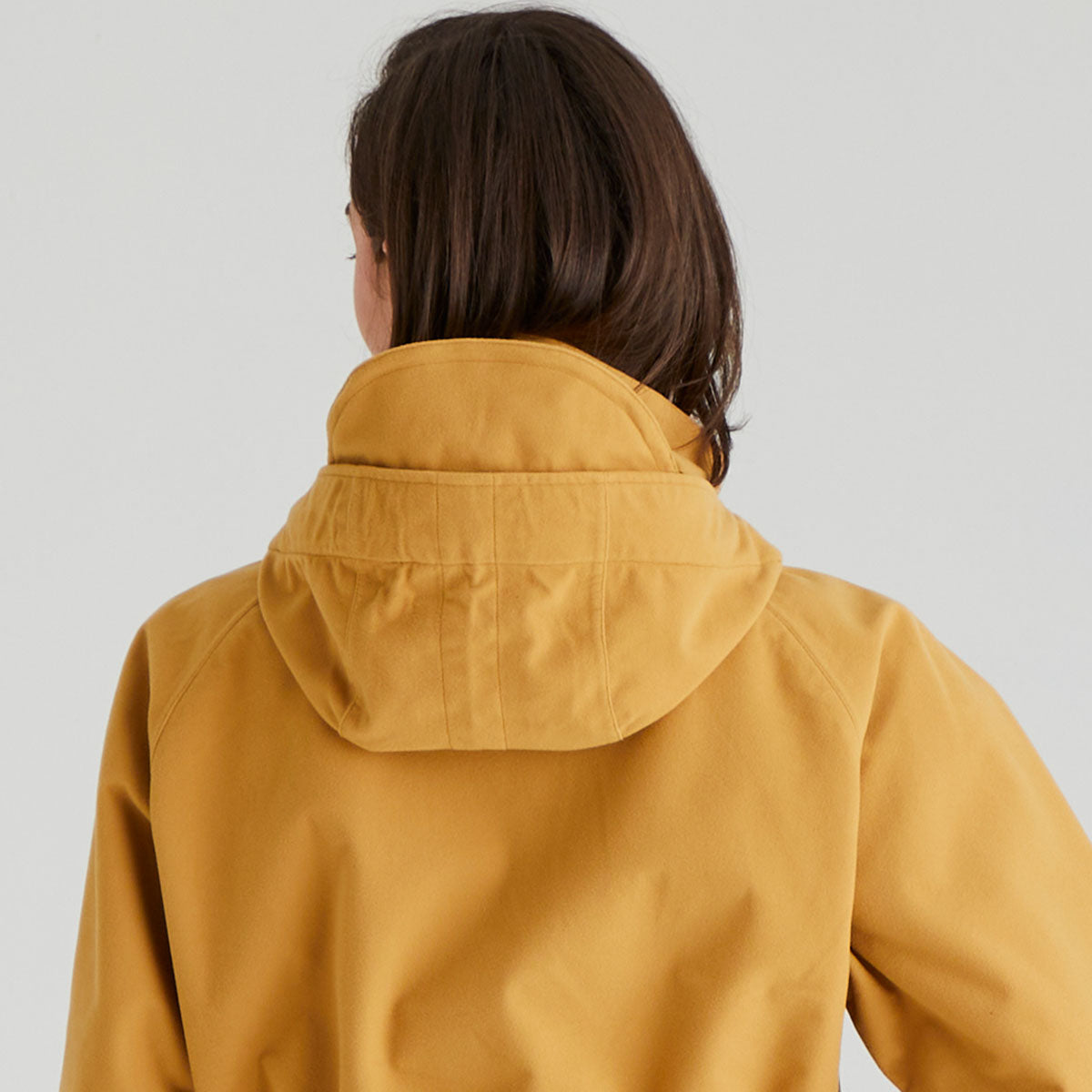 Person wearing a mustard yellow raincoat against a plain background
