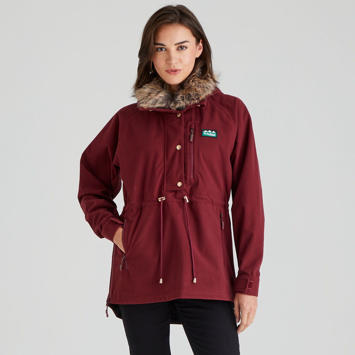 Maroon jacket with fur hood worn by a model on a grey background