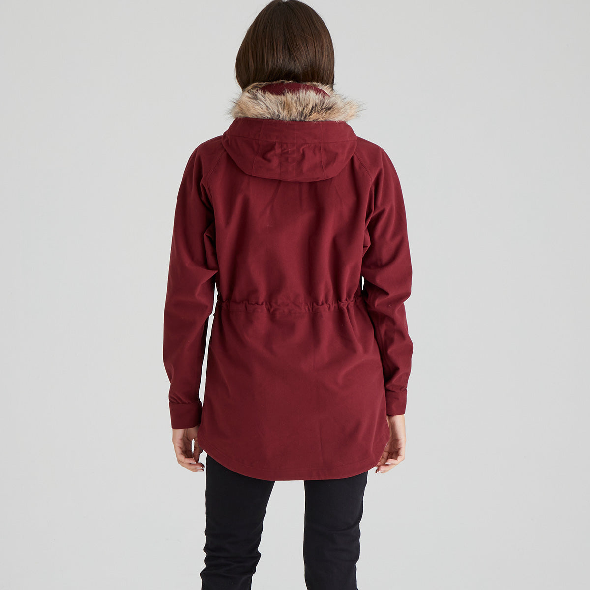 Person wearing a red parka with fur hood on a light grey background