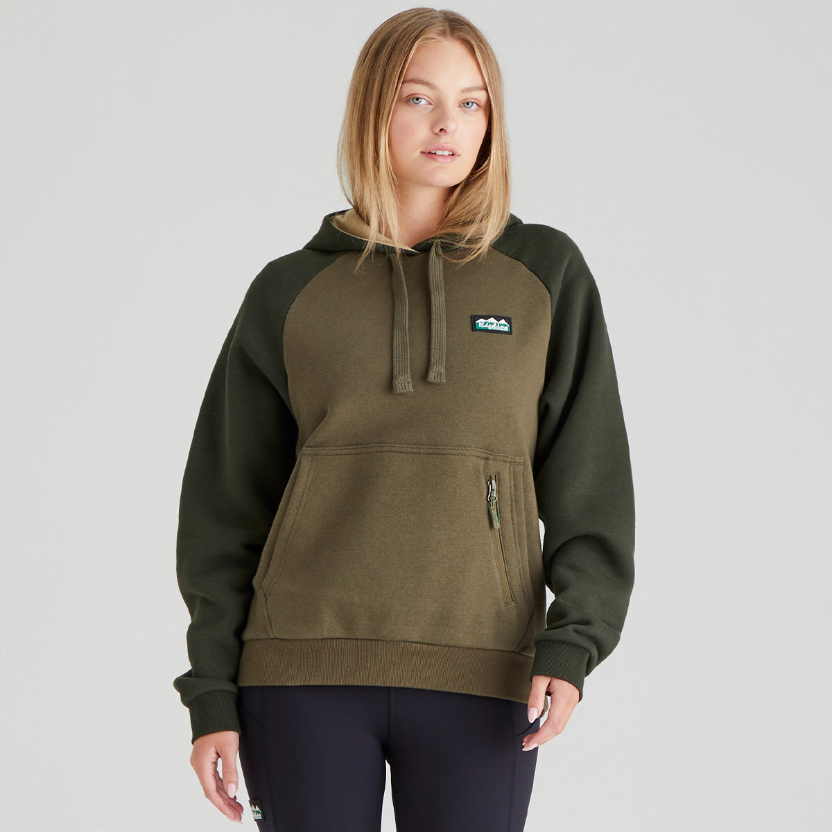 Person wearing a green hoodie with a logo on a grey background