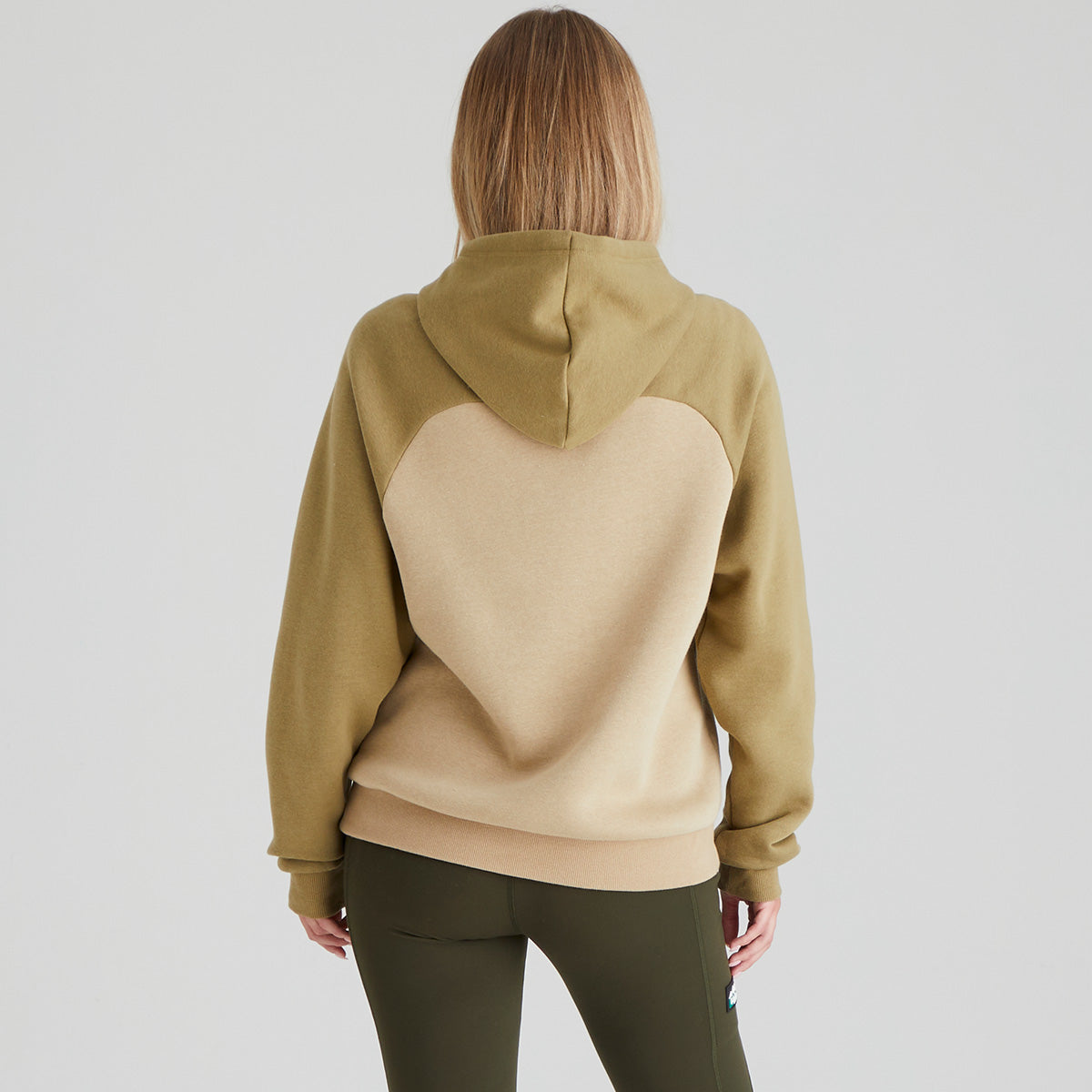 back of person wearing a two-tone hoodie with a plain background