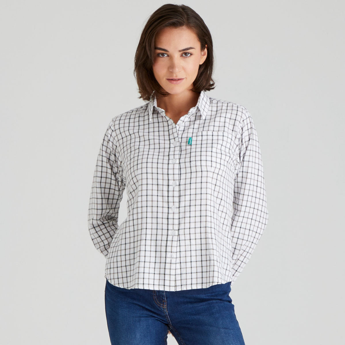 Woman wearing a checkered shirt and blue jeans on a grey background