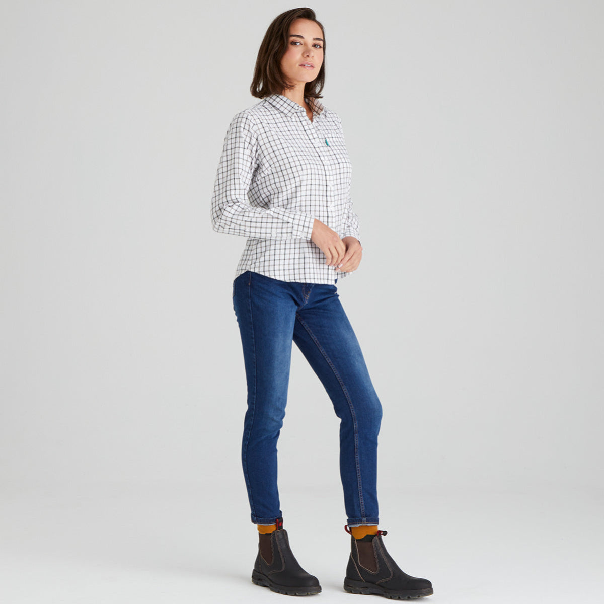 Woman wearing a checkered shirt and blue jeans on a grey background