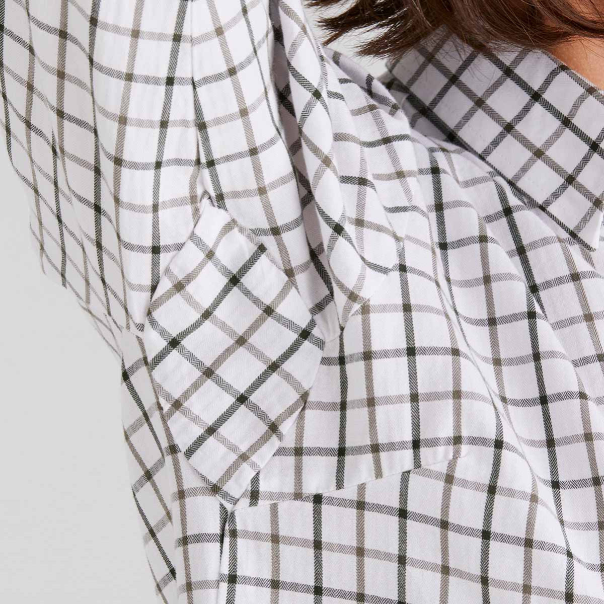Close-up of a checkered fabric with green and olive lines on a plain background