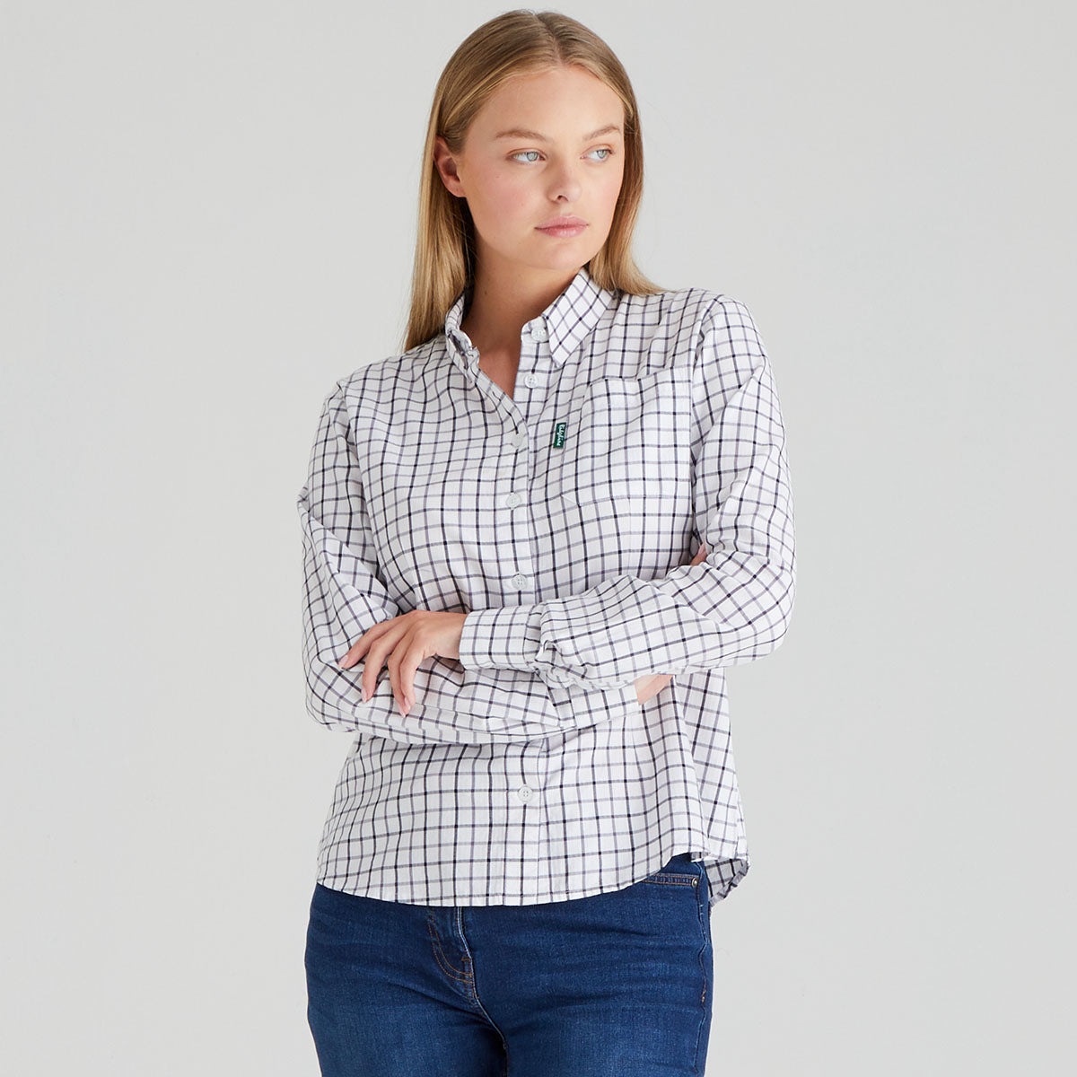 Woman wearing a checkered shirt and jeans on a grey background