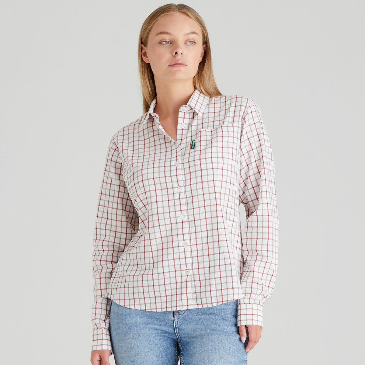 Woman wearing a plaid shirt and jeans on a grey background