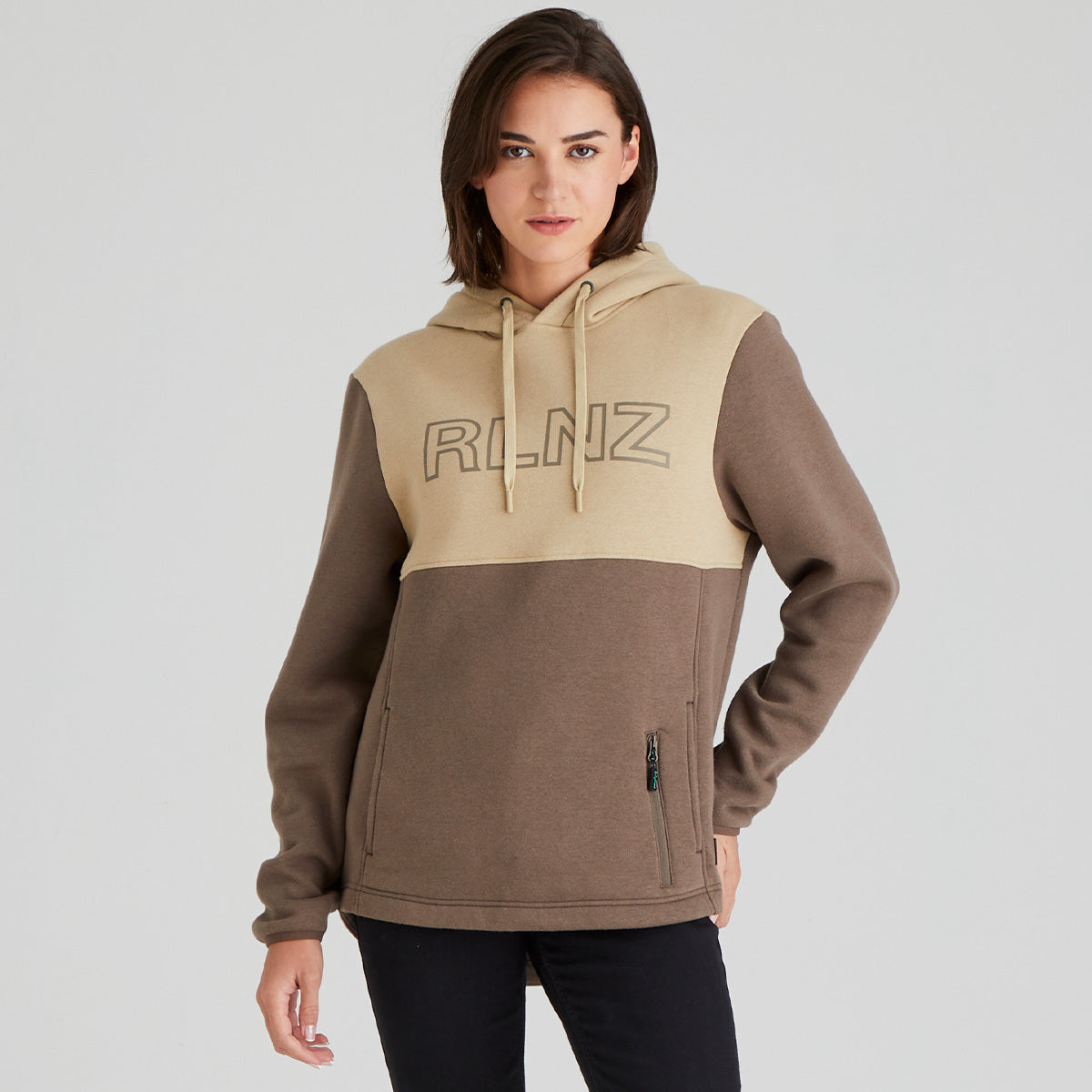 Woman wearing a two-tone hoodie with 'RLNZ' branding on a light grey background