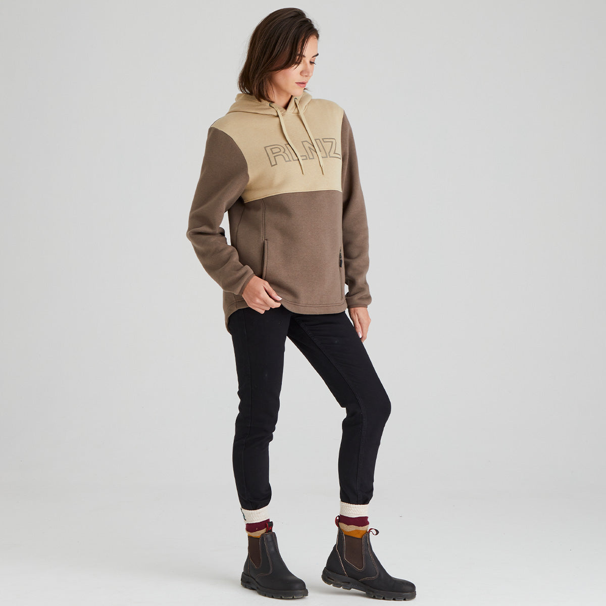 Person wearing a two-tone hoodie with 'RLNZ' branding on a light grey background