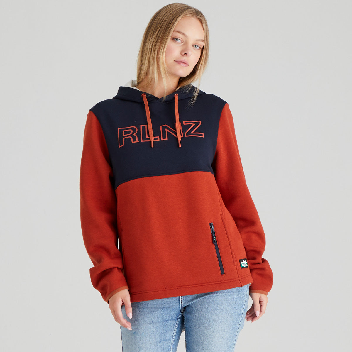 Person wearing a orange and navy hoodie with 'RLNZ' branding on a grey background