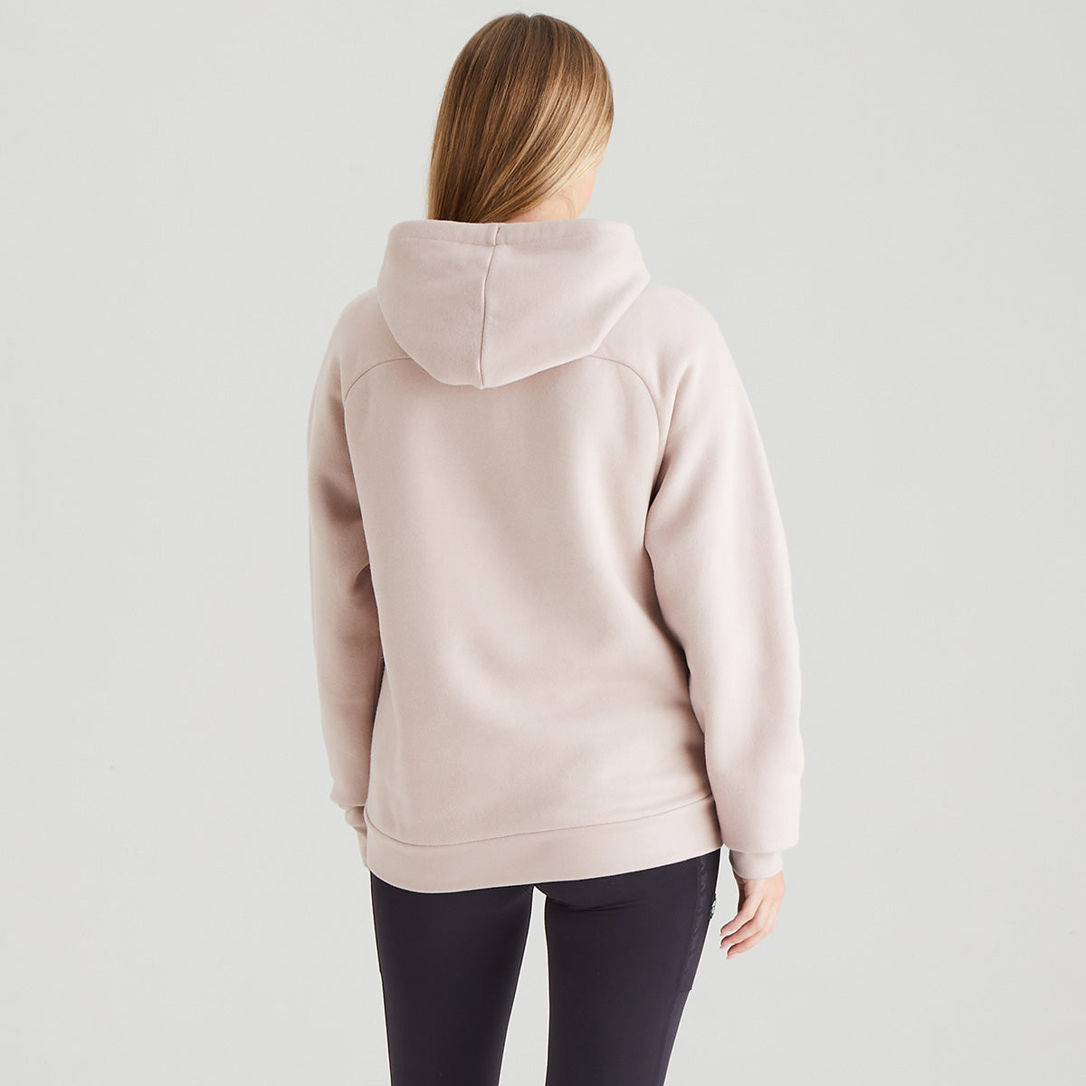 Person wearing a light pink hoodie on a plain background