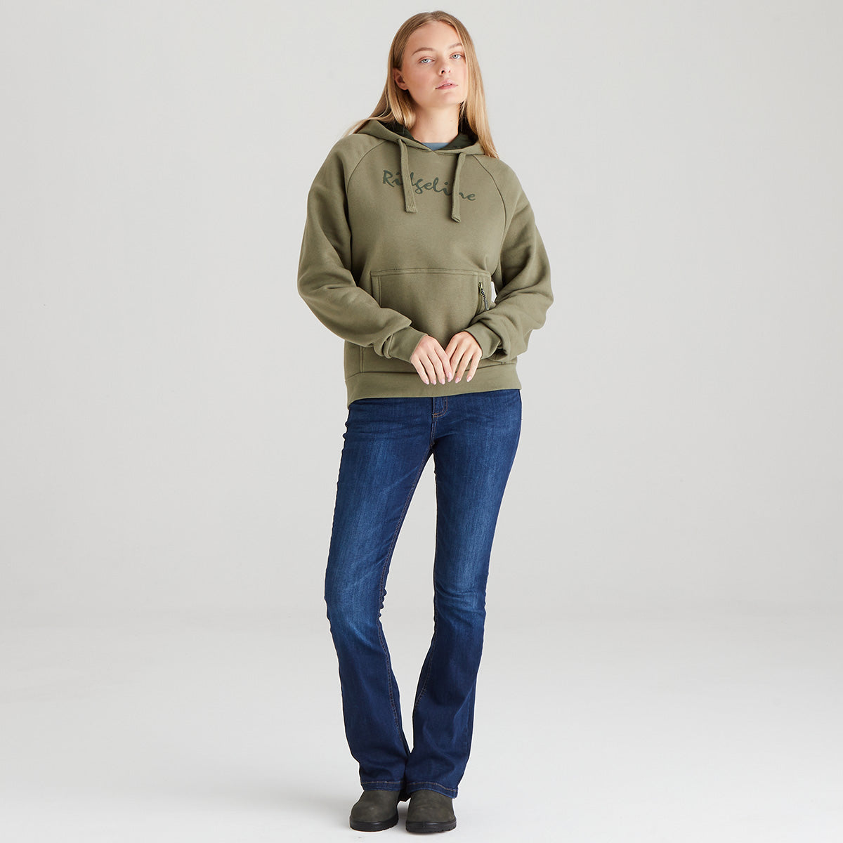 Person wearing a green hoodie and blue jeans on a light gray background