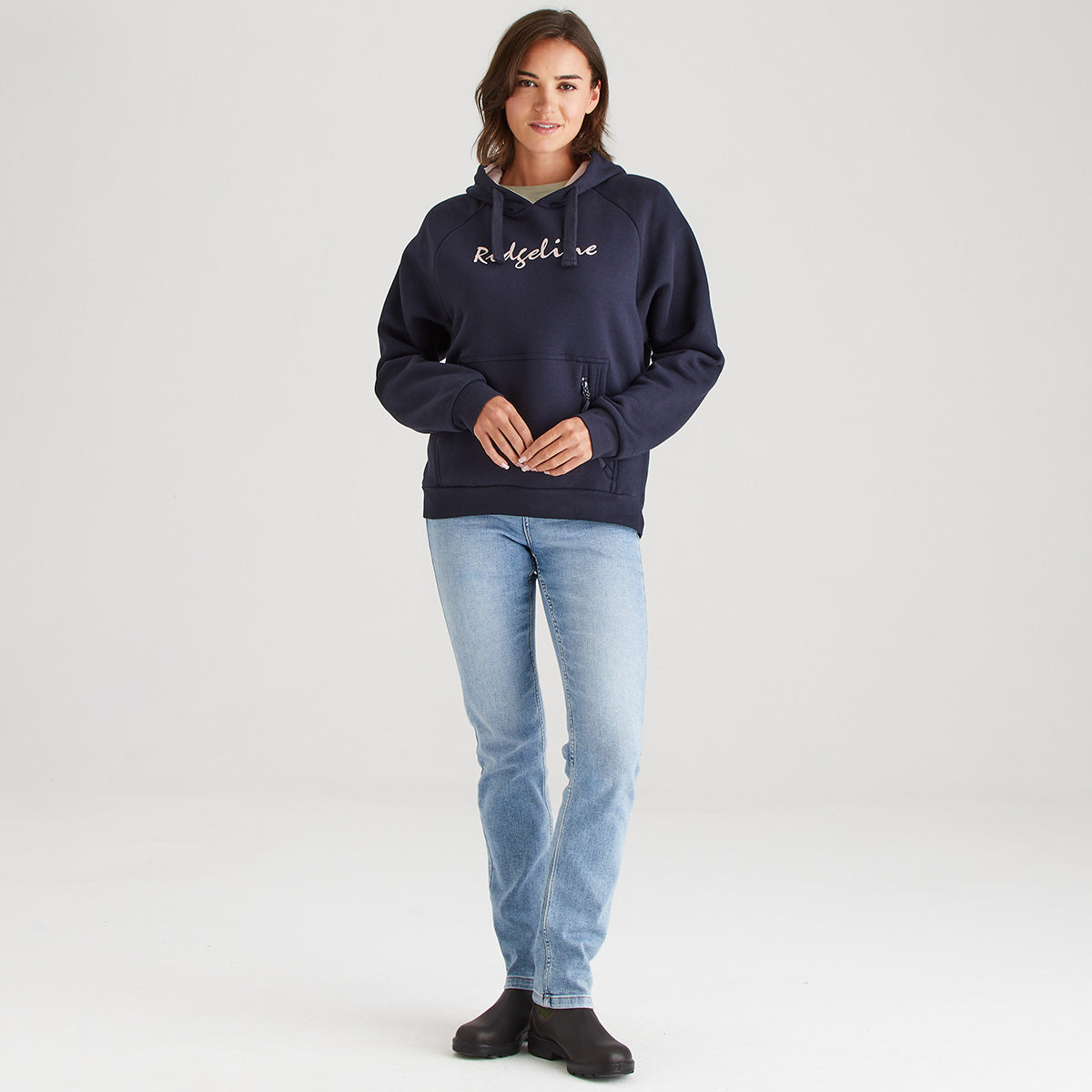 Woman wearing a navy hoodie with text and light blue jeans on a white background