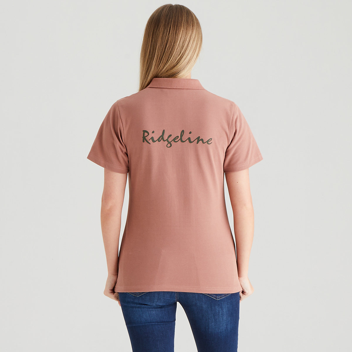 Person wearing a pink polo shirt with 'Ridgeline' branding on the back against a white background