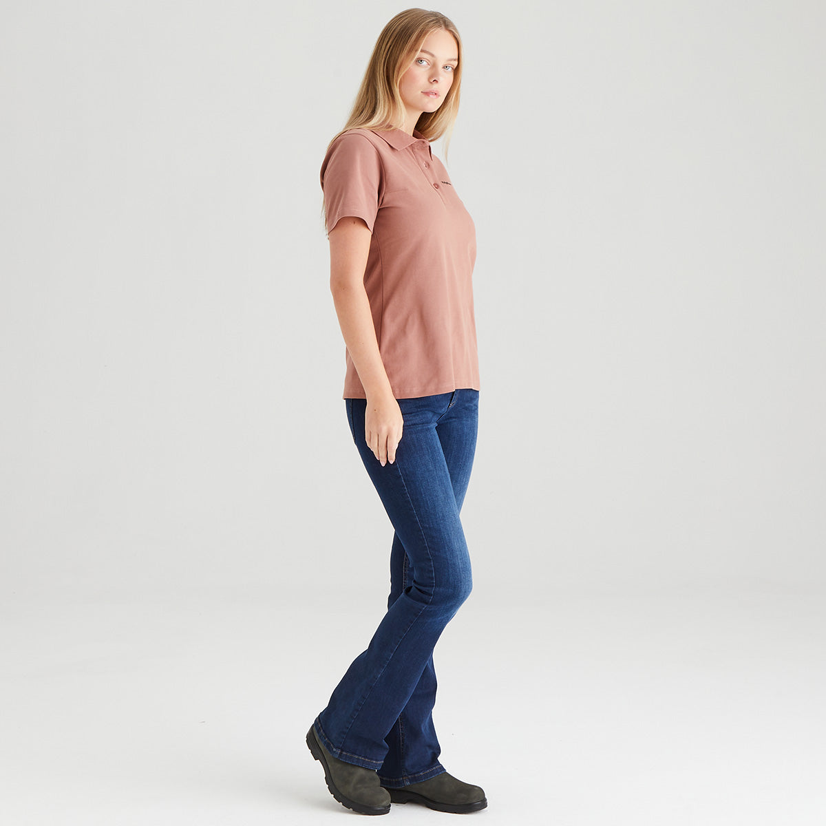 Woman wearing a pink shirt and blue jeans on a white background