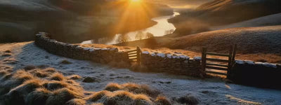 Sunrise over hills with snow and a river.